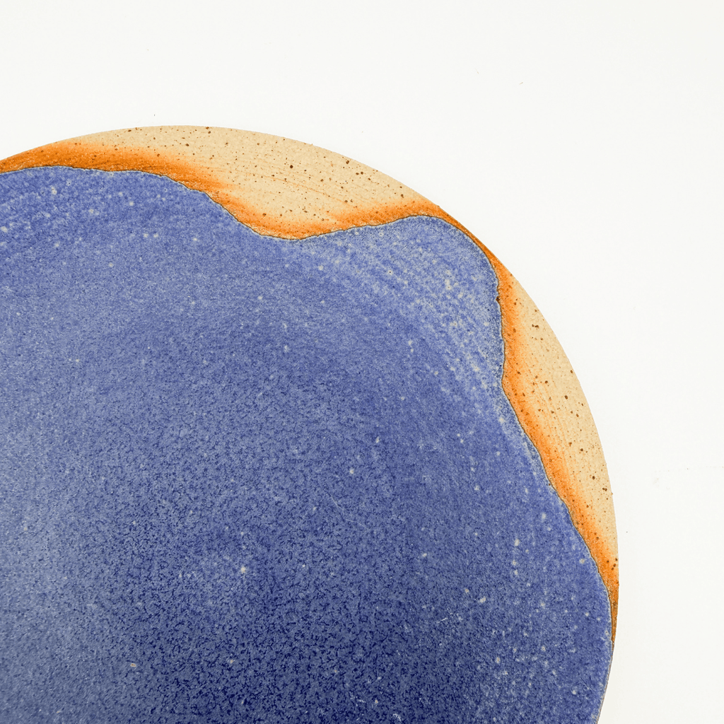 Close-up of a blue and orange textured plate on a white background