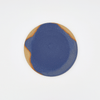 Round ceramic plate with blue and brown design on a white background