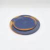 Two blue ceramic plates with brown rims on a white background