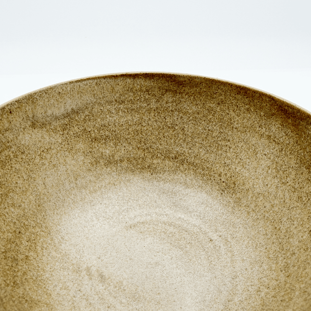 Close-up of a brown ceramic bowl with a textured surface on a white background