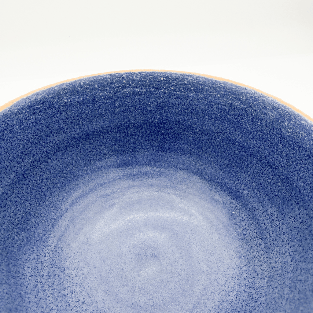 Close-up of a blue ceramic bowl with a textured surface on a white background