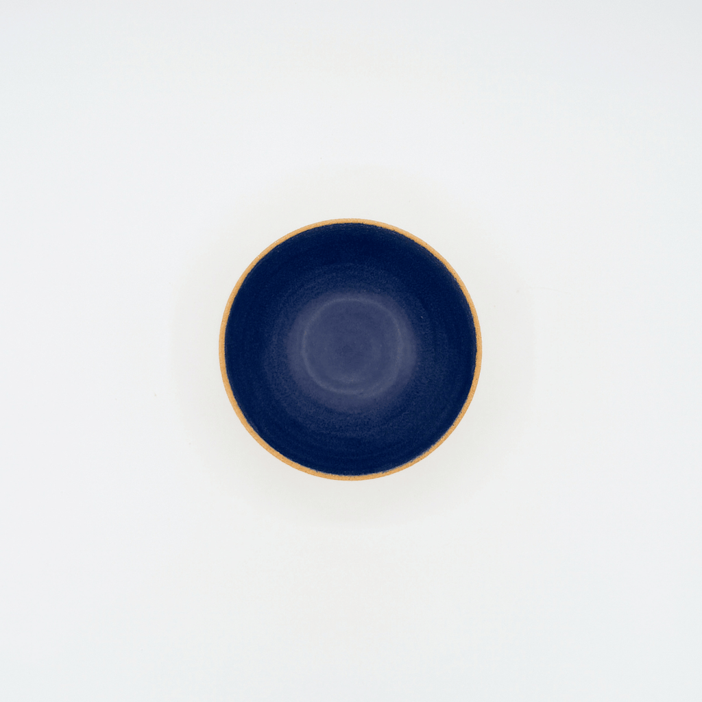 Navy blue ceramic bowl with beige rim on a white background
