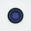 Two navy blue bowls with beige rims on a white background