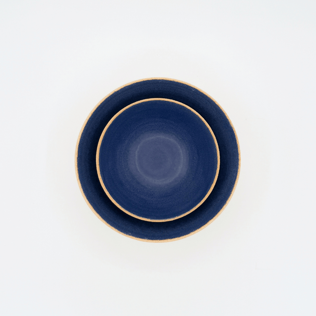 Two navy blue bowls with beige rims on a white background