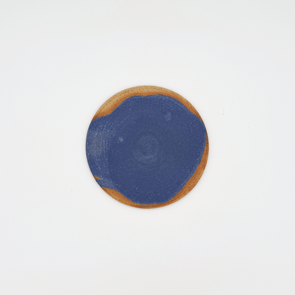 Round ceramic plate with blue center and brown rim on a white background