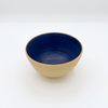Ceramic bowl with blue interior and beige exterior on a white background