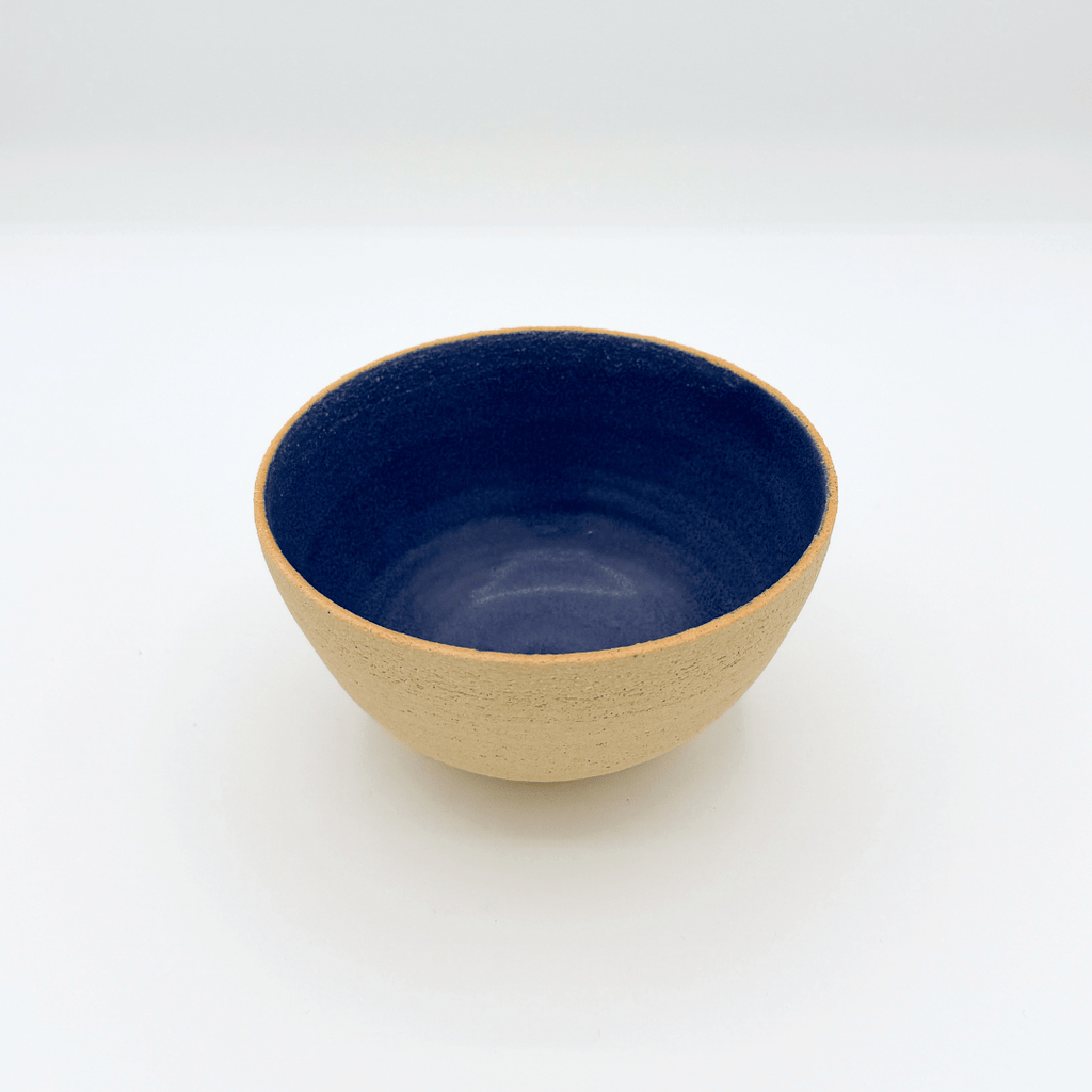 Ceramic bowl with blue interior and beige exterior on a white background
