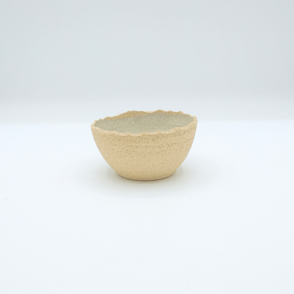 Small ceramic cup with textured surface on a white background