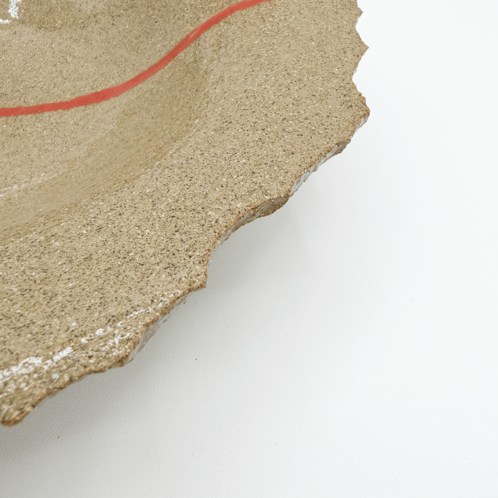 close up of stoneware plate with red line detail on white background