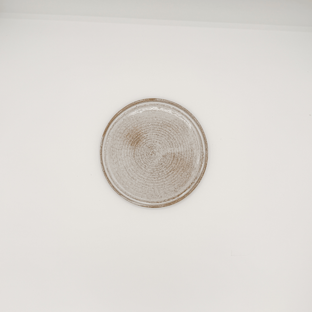Round ceramic plate with textured edge on a white background
