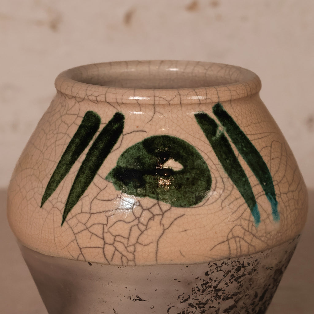 A handmade ceramic planter pot with a beige crackled glaze, featuring green painted abstract leaf-like stripes and a central green oval motif on the front.