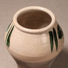 A ceramic vase with a cream-colored glaze featuring a crackle pattern and hand-painted green leaf motifs, shown from a top-down angle on a neutral gray background.