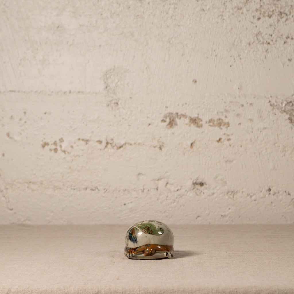 Small ceramic turtle with floral design on a textured surface