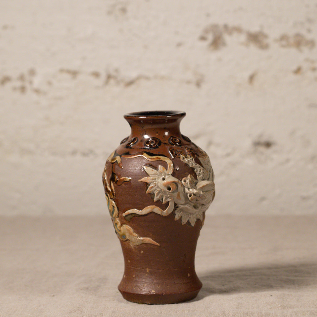Decorative brown vase with floral patterns on a textured surface