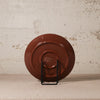 Brown ceramic plate on a stand against a textured beige wall