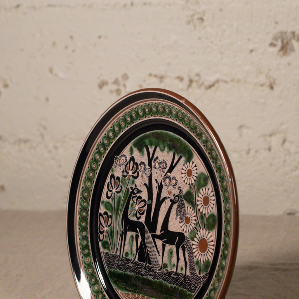 Decorative plate with deer and floral design on a textured surface