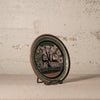 Decorative plate with animal design on a stand against a textured wall.