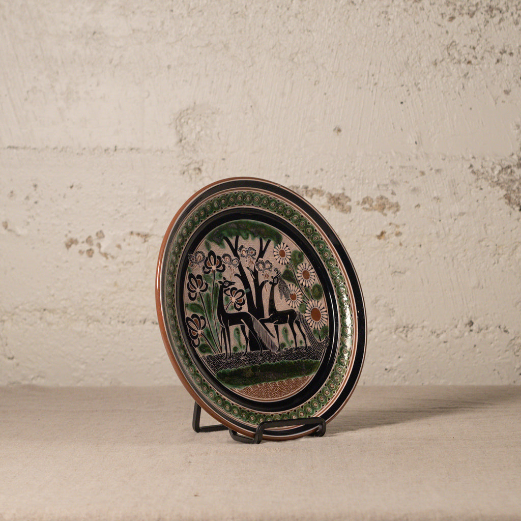 Decorative plate with animal design on a stand against a textured wall.