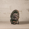 Decorative plate with a deer design on a stand against a textured wall.