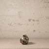 Small ceramic turtle with floral patterns on a textured surface and beige background