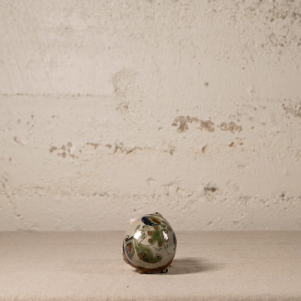 Small ceramic turtle with floral patterns on a textured surface and beige background