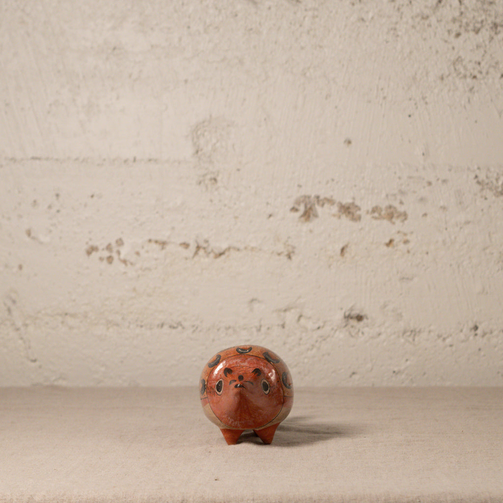Small ceramic armadillo with decorative design on a textured surface