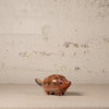 Ceramic hedgehog figurine on a textured surface with a neutral background