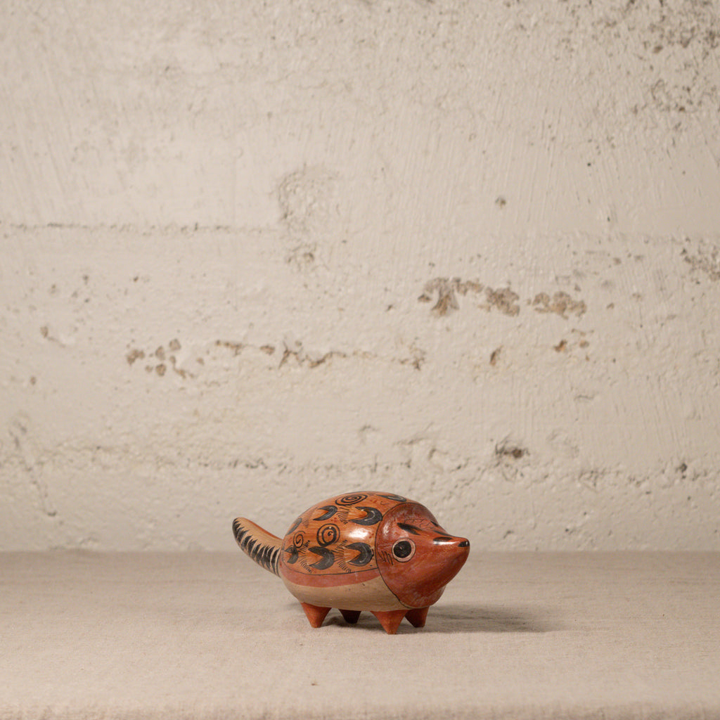 Ceramic hedgehog figurine on a textured surface with a neutral background