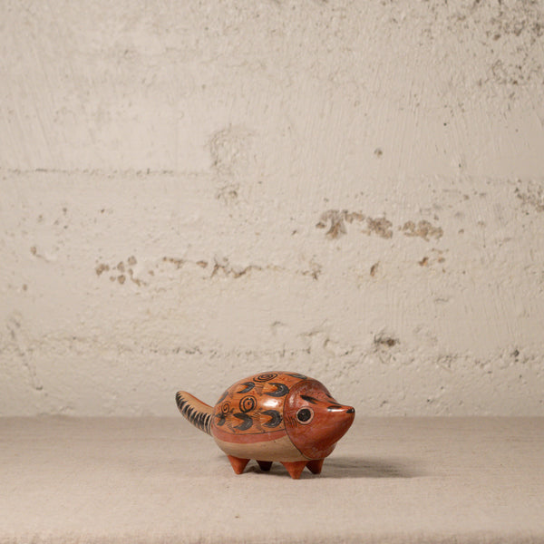 Ceramic hedgehog figurine on a textured surface with a neutral background