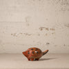 Small ceramic animal figurine on a textured surface with a neutral background