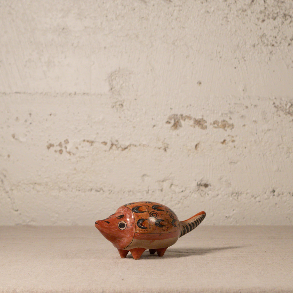 Small ceramic animal figurine on a textured surface with a neutral background