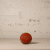 Red ceramic vase on a textured surface with a neutral background