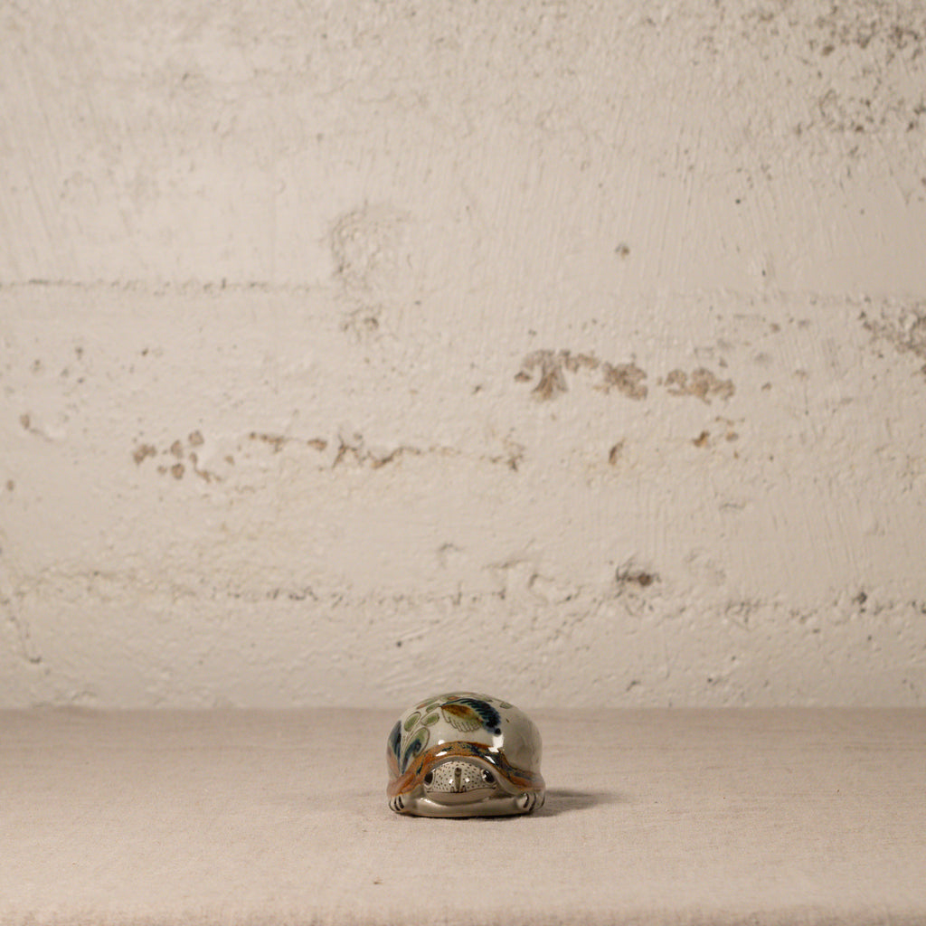 Small decorative turtle on a textured surface with a neutral background