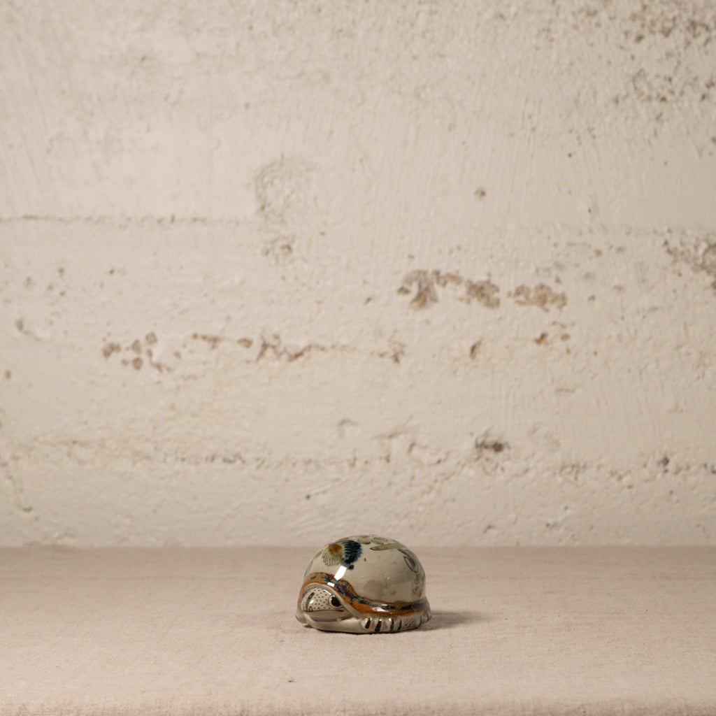 Small ceramic turtle on a textured beige surface with a neutral background