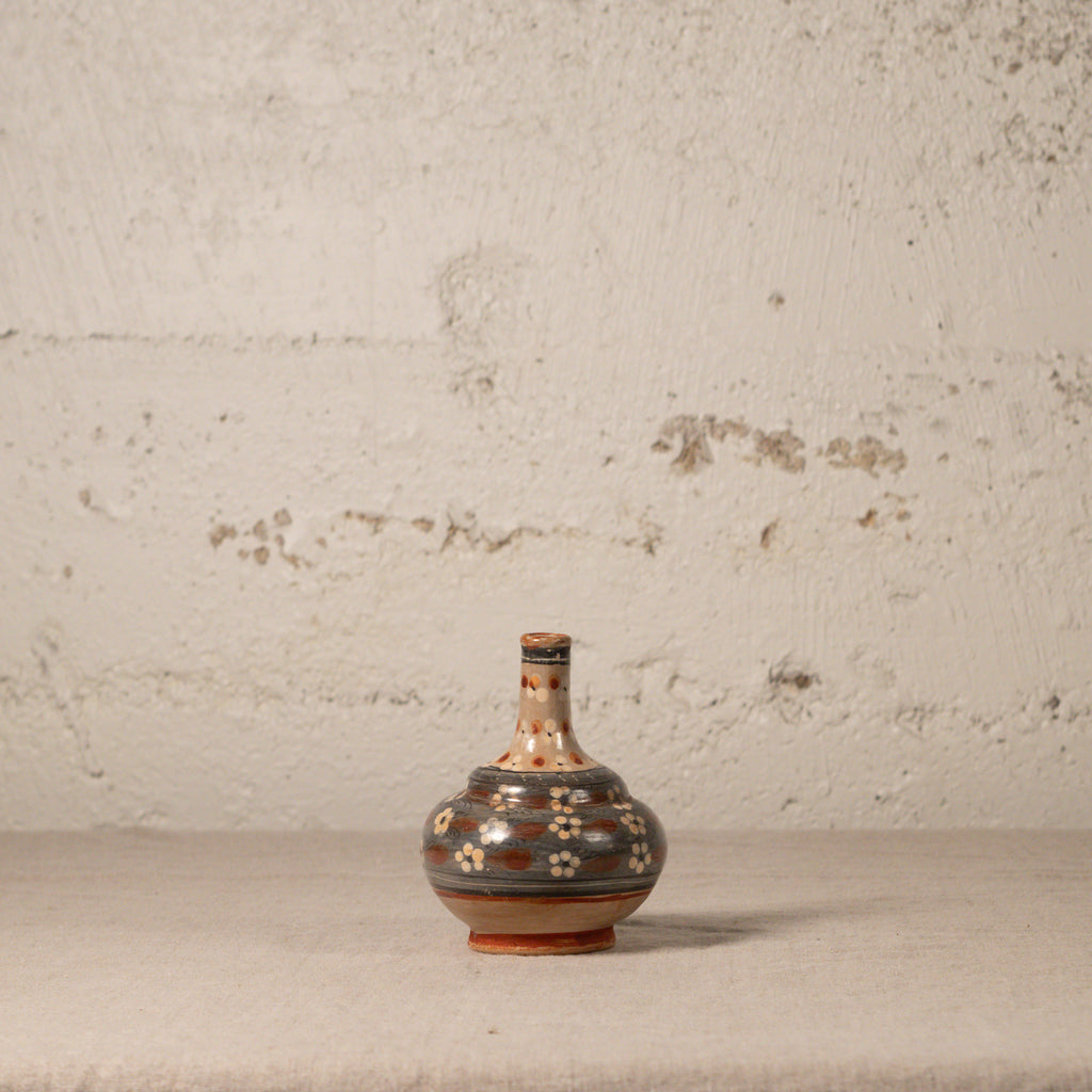 Decorative ceramic vase with floral patterns on a textured surface and light gray background
