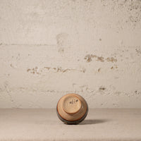 Small ceramic cup with 'MEXICO' written on it against a textured beige wall.