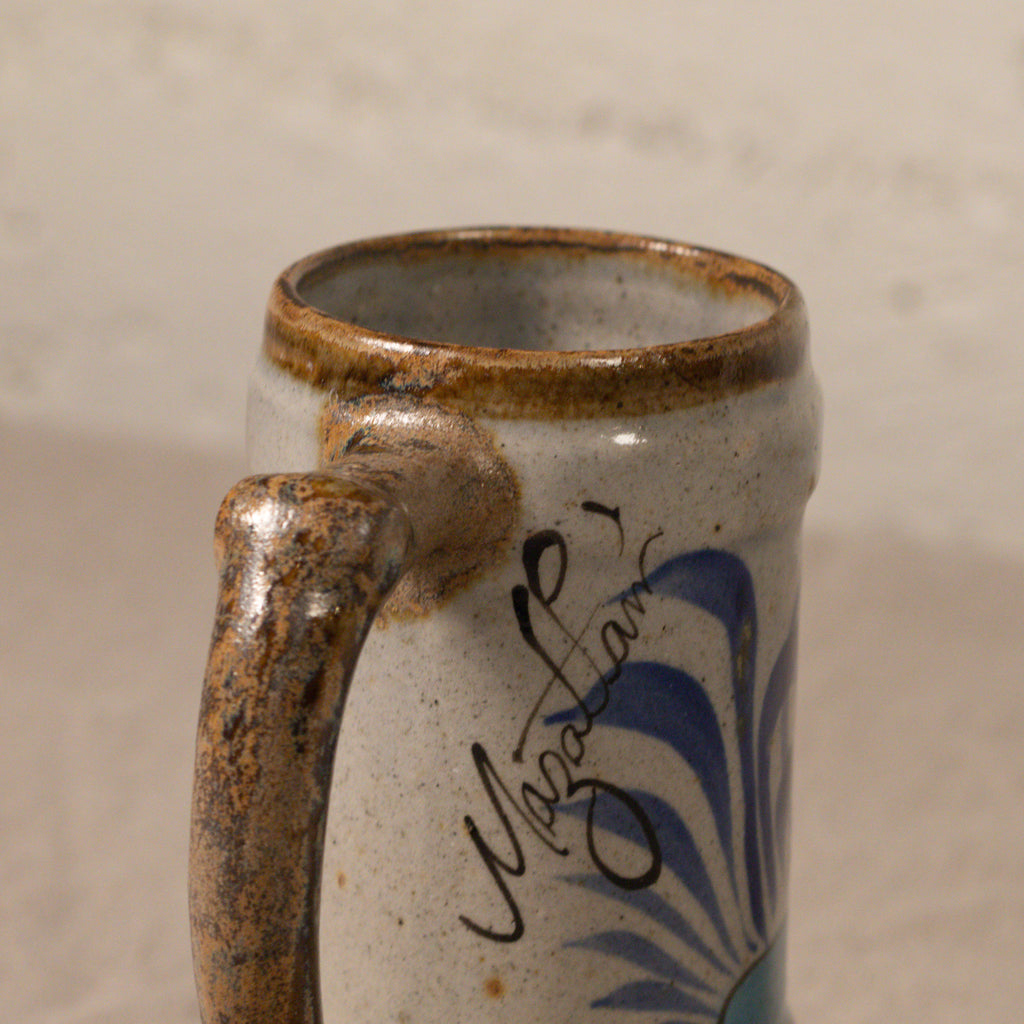 Ceramic mug with a handle and decorative elements on a plain background