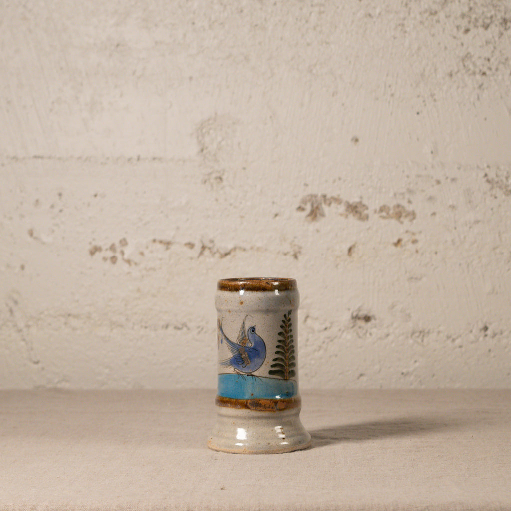 Small ceramic vase with decorative design on a textured surface and background