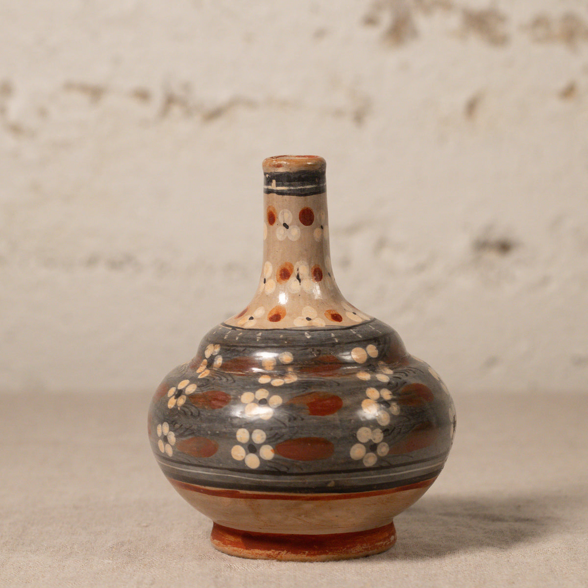 Ceramic bottle with decorative patterns on a textured surface