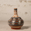 Ceramic bottle with decorative patterns on a textured surface
