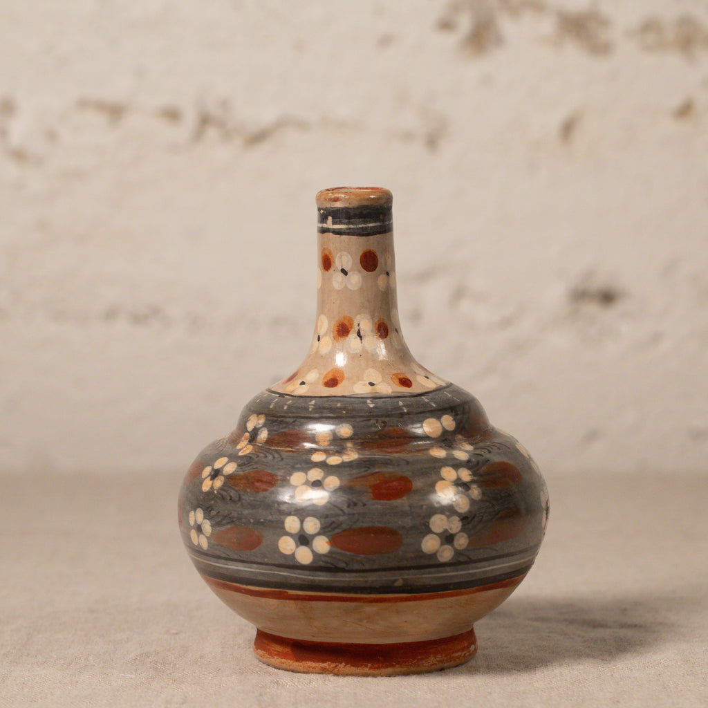 Ceramic bottle with decorative patterns on a textured surface