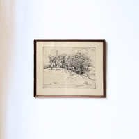 Framed black and white landscape drawing on a white wall