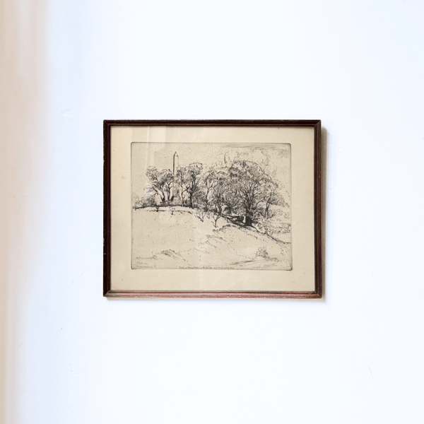 Framed black and white landscape drawing on a white wall