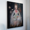 A vertical canvas wall art print featuring a surreal painted portrait of a woman in a pale dress holding flowers, displayed against a plain white wall.