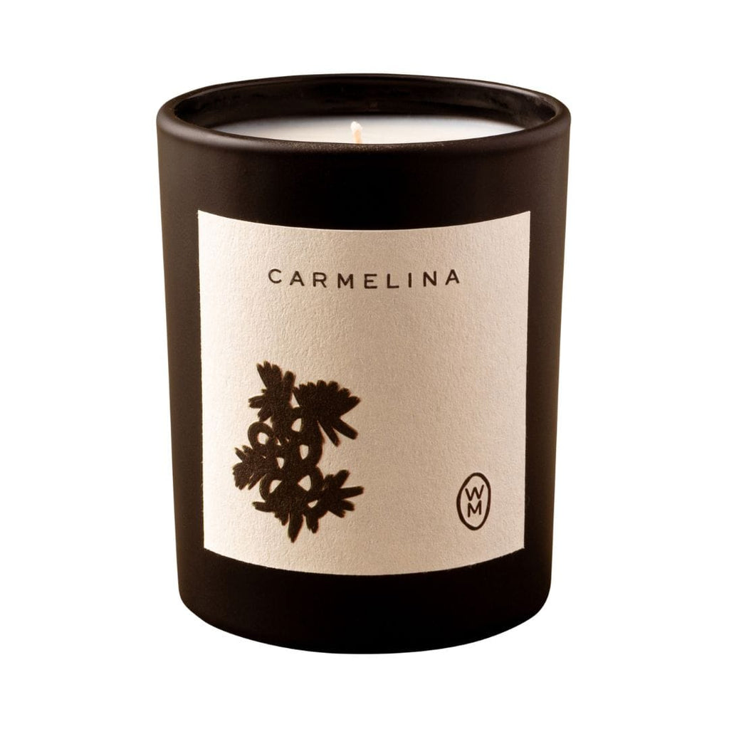 Candle in a black container with 'Carmelina' label on a white background