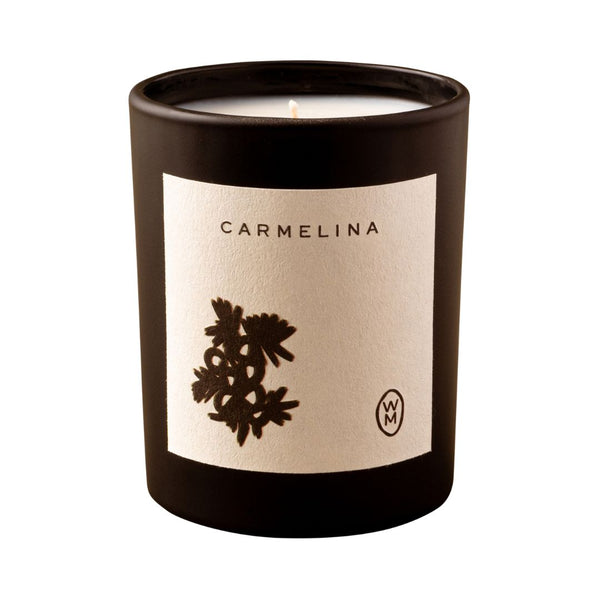 Candle in a black container with 'Carmelina' label on a white background
