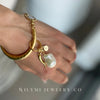 Gold bracelet with a pearl charm on a blurred background, featuring WILYMI JEWELRY CO branding.