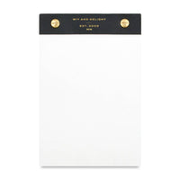 A white notepad with a black top header band featuring gold text that reads 'WIT AND DELIGHT EST. 2009 MN' and two gold rivets on either side, shown on a plain white background.