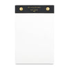 A white notepad with a black top header band featuring gold text that reads 'WIT AND DELIGHT EST. 2009 MN' and two gold rivets on either side, shown on a plain white background.