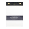 A Wit and Delight Desktop Notepad with cream-colored sheets, a dark charcoal gray top header, a matching dark gray middle band, and two gold metal grommets at the top.